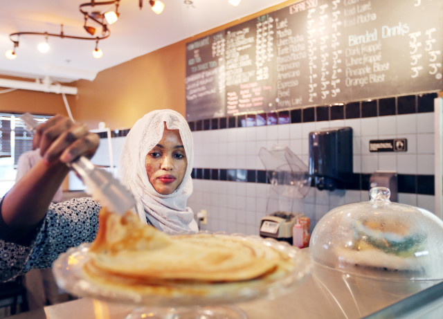JERRY HOLT – STAR TRIBUNE Bulbulo Mohamud lifted a piece of malawax (similar to a pancake) for a customer at her cafe.